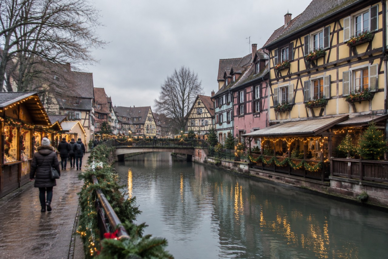 Festive chalets and warm string lights along a canal in Colmar's old town