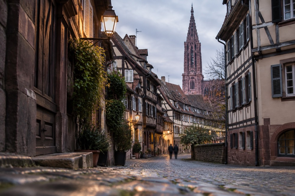 A lamplit lane between medieval houses in the evening