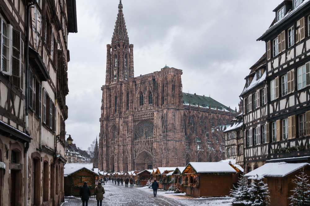 A snowy square with market chalets in front of a cathedral facade