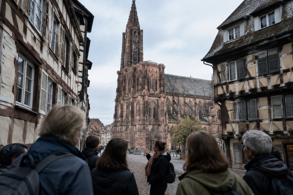 Tour group listening to a guide in a narrow old-town street in Strasbourg
