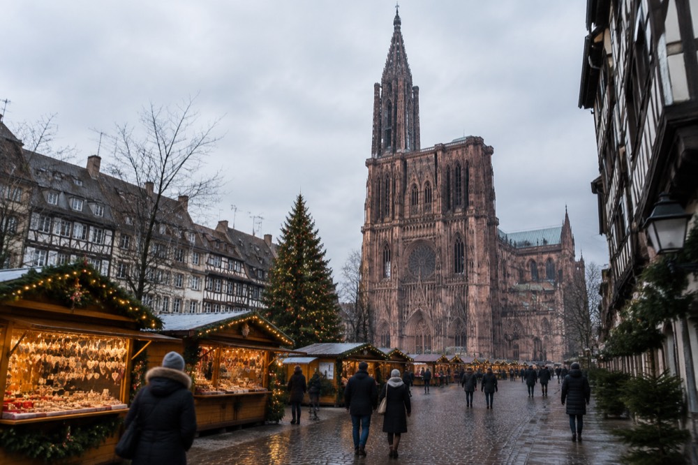 Illuminated Christmas market chalets and a decorated tree in a Strasbourg square