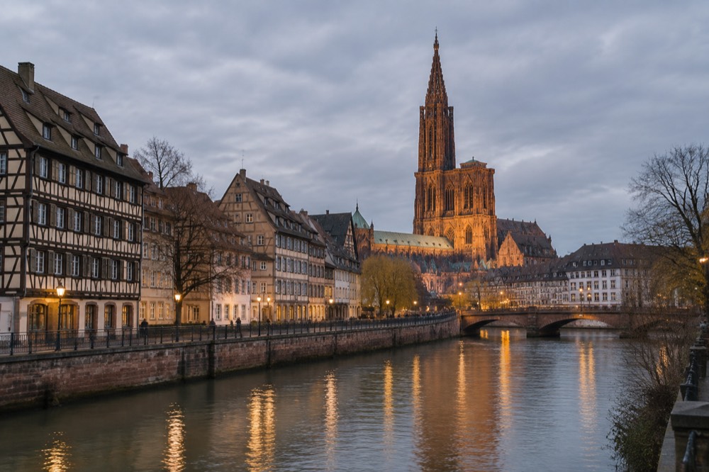 Riverside quay at dusk with the cathedral lit in the distance in Strasbourg