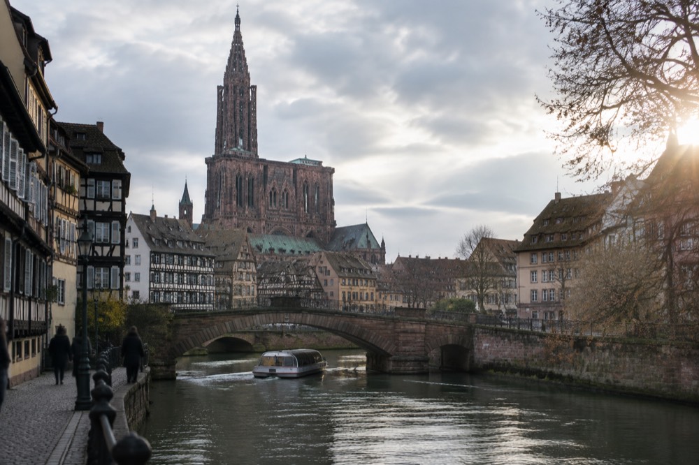 A river boat passing under a stone bridge on the Ill in central Strasbourg
