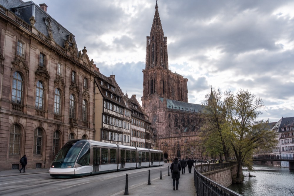 A tram passing the ornate facade of a museum building on a wide Strasbourg avenue