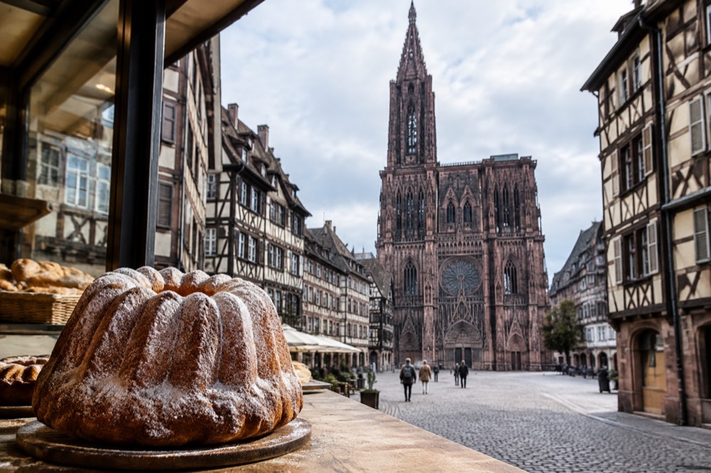 A kougelhopf ring cake with fluted sides and icing sugar on a bakery counter in Strasbourg