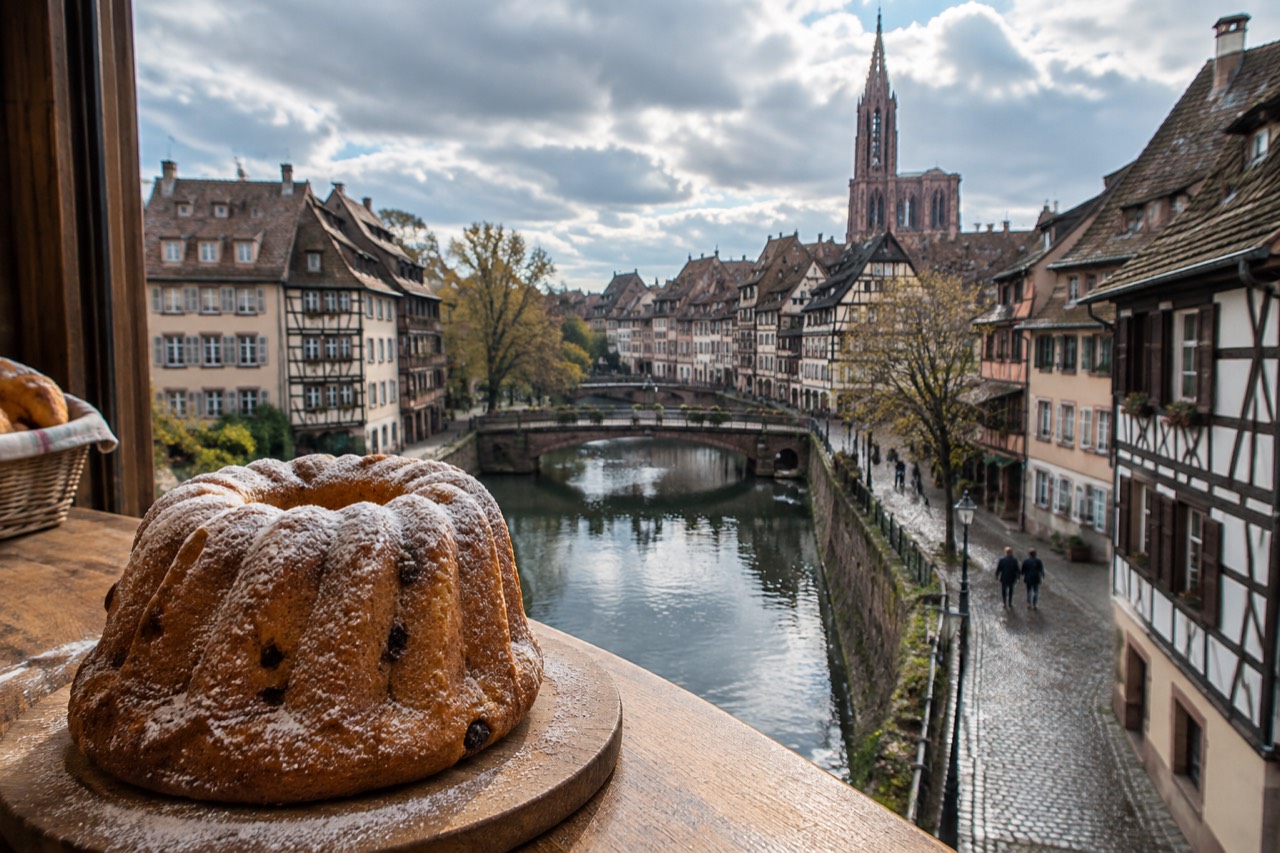 A freshly baked kougelhopf ring cake dusted with icing sugar on a wooden bakery counter