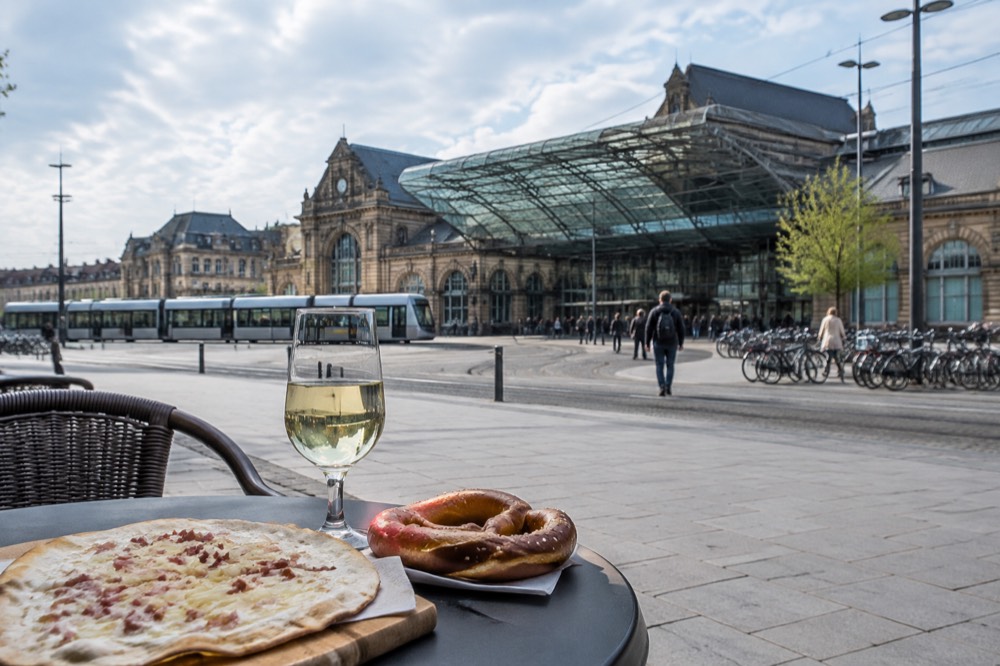 A table with an Alsatian flatbread, a glass of white wine and a pretzel