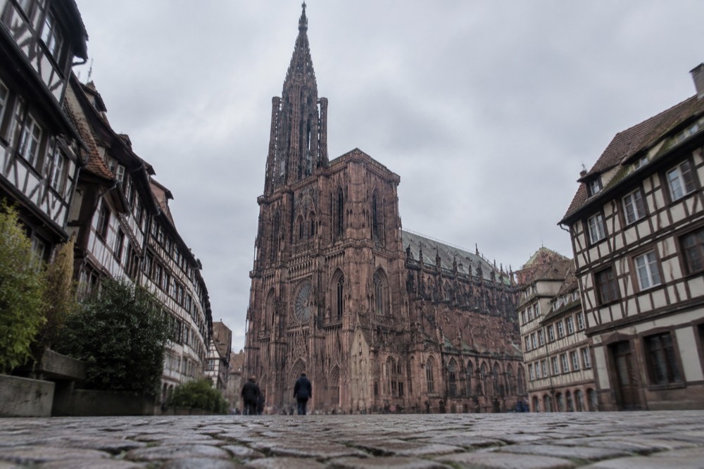 A Gothic cathedral spire rising above red-roofed old city rooftops