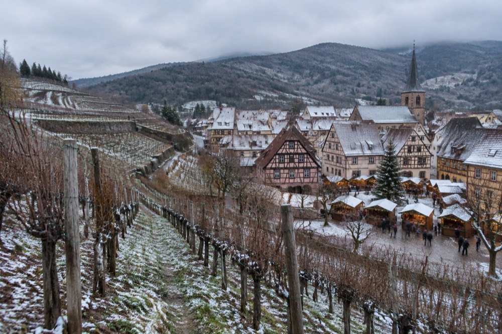 A small Christmas market with wooden chalets in a snowy village square