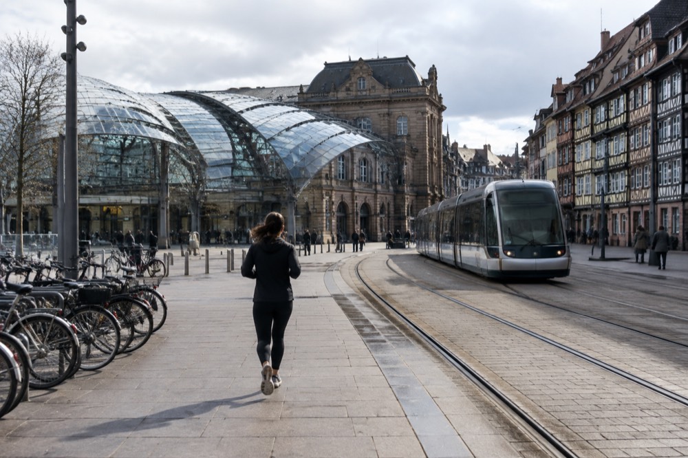 A modern tram gliding along a street of half-timbered buildings in a French city centre