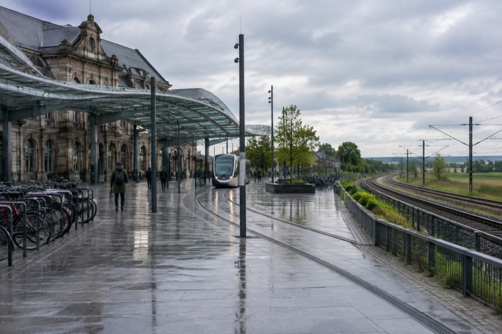 Railway tracks leaving a station through open countryside with fields on both sides