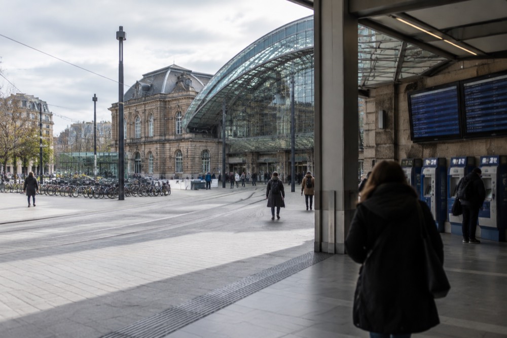 A station concourse with a departures board and ticket machines along the wall