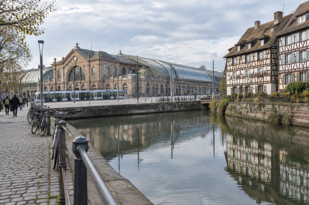 Half-timbered houses reflected in a calm canal along a cobbled quayside