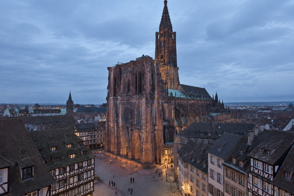 A Gothic cathedral facade rising above a square of old stone buildings