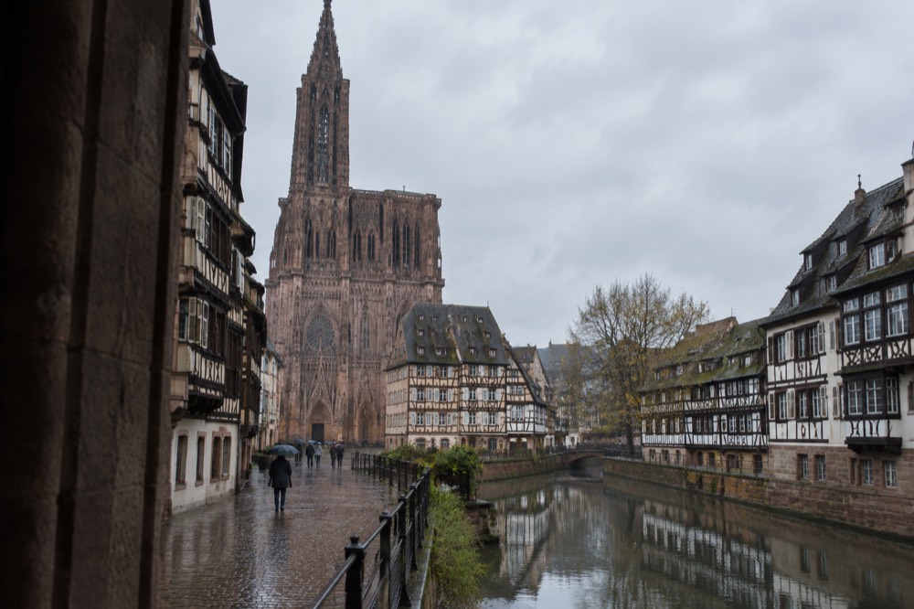 A canal in Strasbourg reflecting half-timbered houses on a calm morning