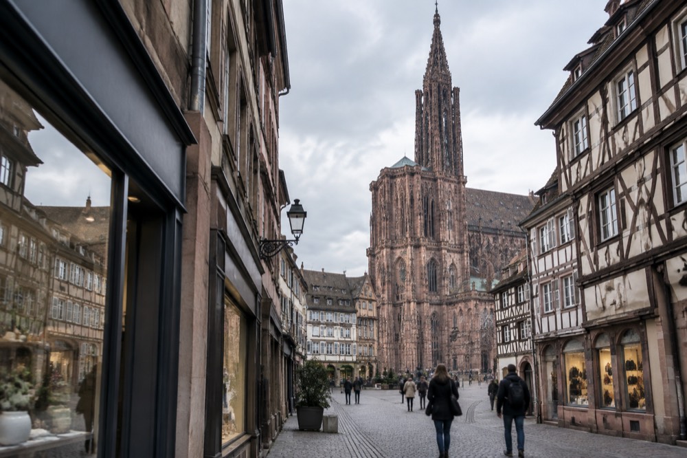 A pedestrian shopping street in central Strasbourg lined with historic buildings and shop windows
