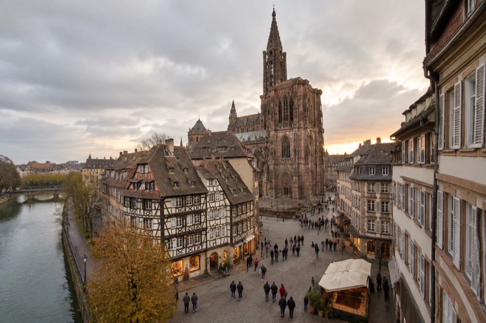 A busy pedestrian shopping street in Strasbourg with historic facades above the shopfronts