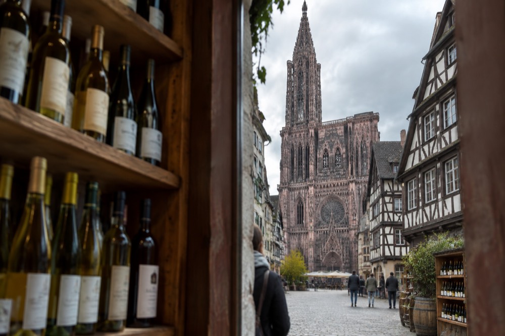 Bottles of Alsatian wine displayed on wooden shelves in a Strasbourg wine shop