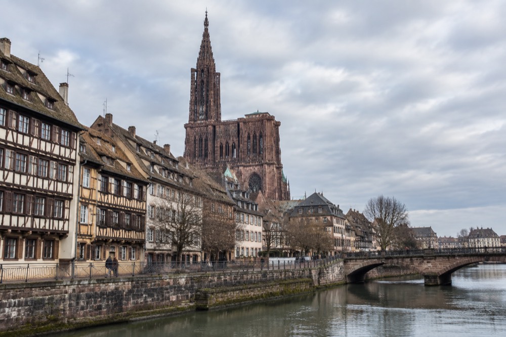 Flat riverside quay in Strasbourg with the cathedral spire rising over the rooftops