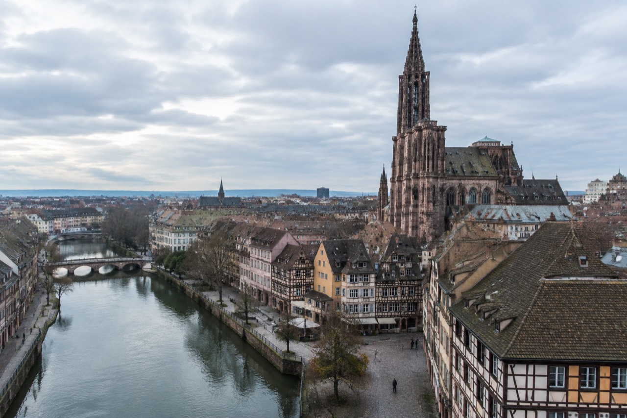 Flat riverside quay in Strasbourg with the cathedral spire rising over the rooftops