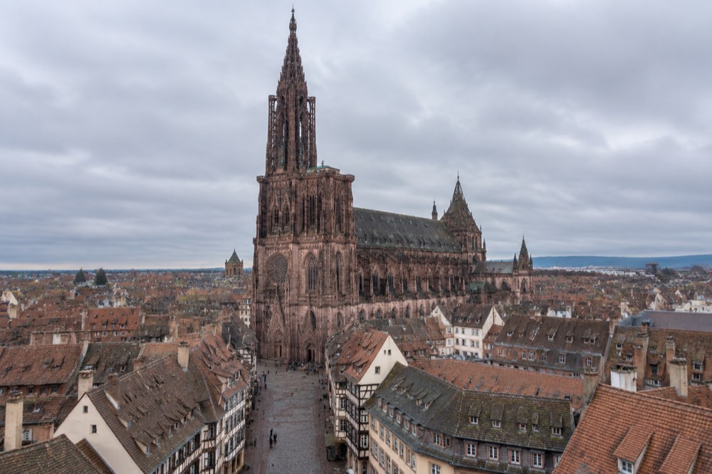 The single spire of Strasbourg Cathedral rising above red-tiled rooftops of the old city