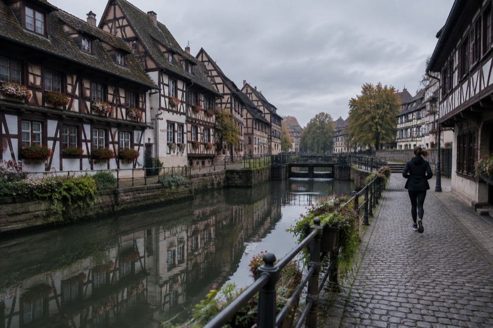 Half-timbered houses reflected in a calm canal in Petite France at golden hour