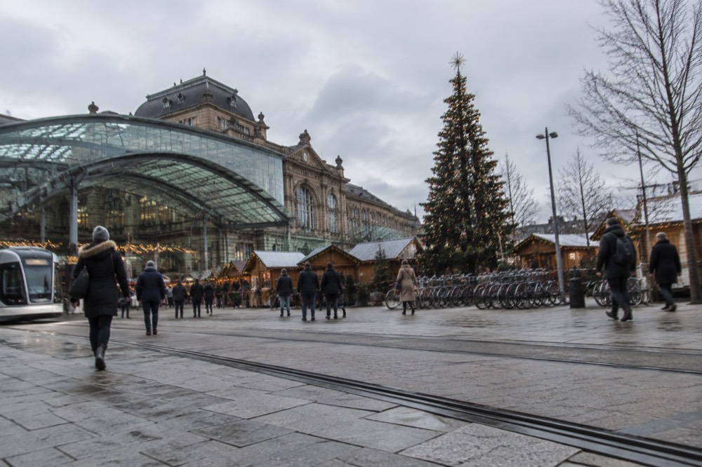 A Christmas market square with wooden chalets, garlands of lights and a tall decorated tree