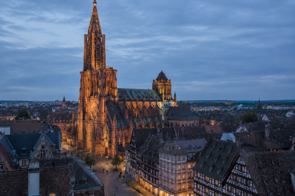 Strasbourg Cathedral lit up at night above the dark rooftops of the old town