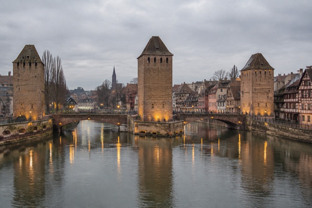 The Ponts Couverts bridges and the Ill river reflecting evening lights in Strasbourg