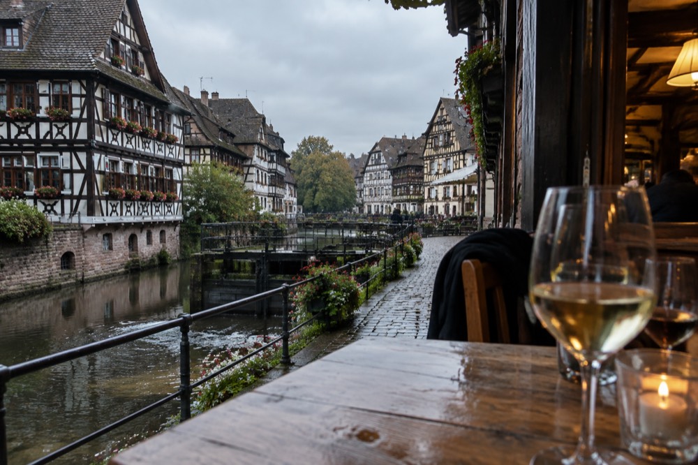 A warm winstub interior with wooden tables and glasses of Alsatian wine in the evening