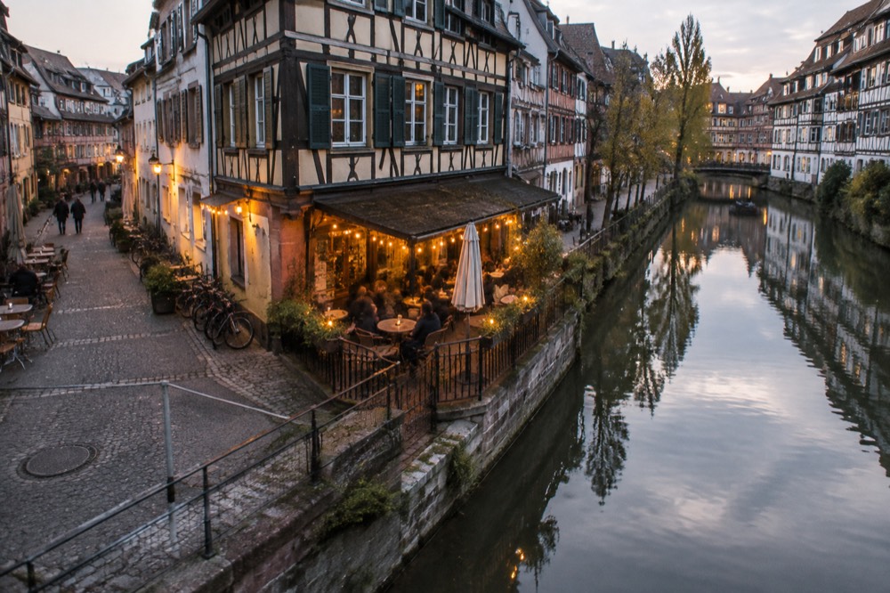 A small lit bar terrace on a corner in the Krutenau quarter of Strasbourg at night