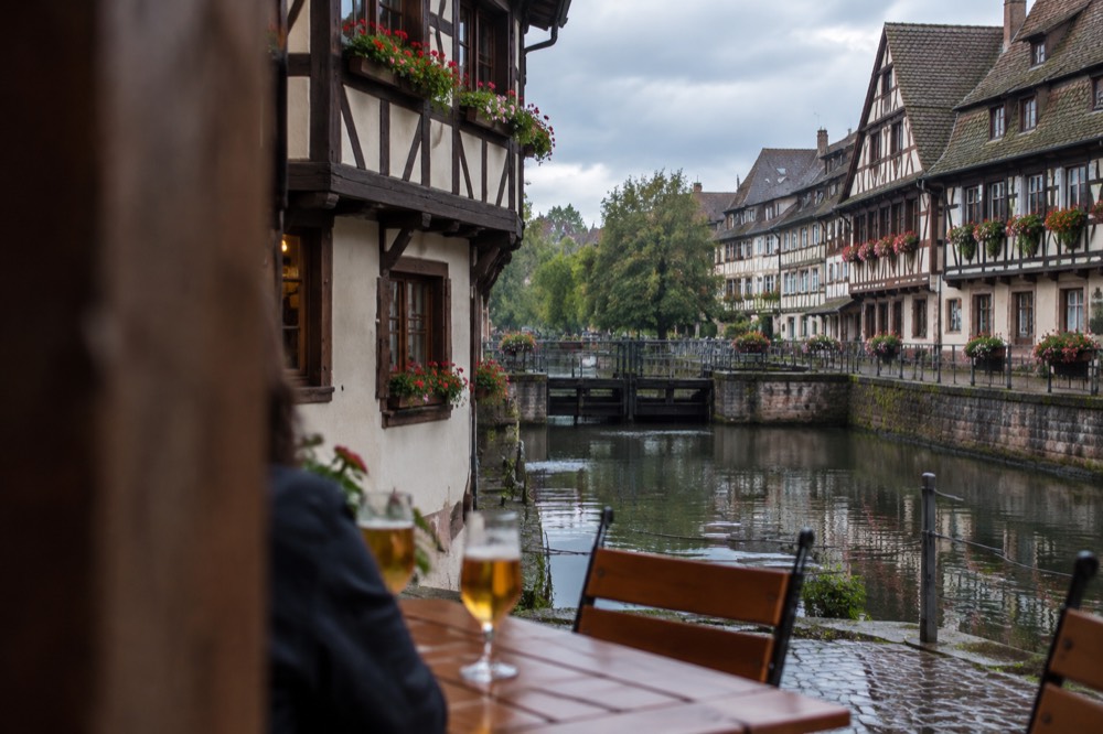 Glasses of beer on a wooden table outside a half-timbered winstub in Strasbourg