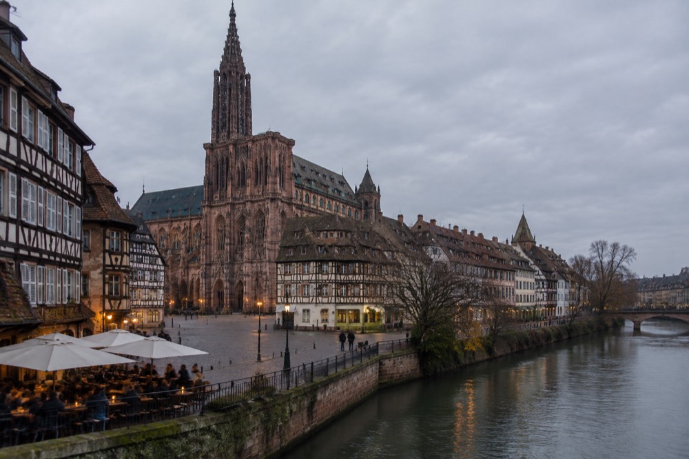 Riverside terrace with drinkers beside the Ill in Strasbourg at dusk