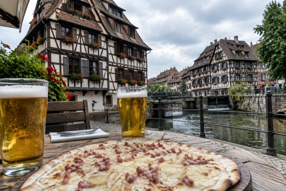 A tarte flambee and two glasses of beer served on a winstub table