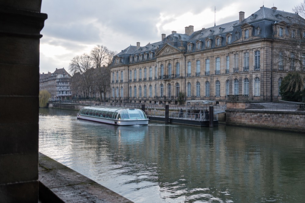 A sightseeing boat approaching the landing stage beside the Palais Rohan on the River Ill in Strasbourg