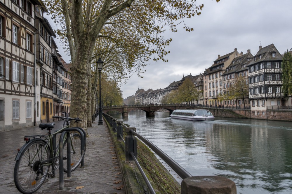 A bicycle locked to a rack on a quiet street with half-timbered buildings behind