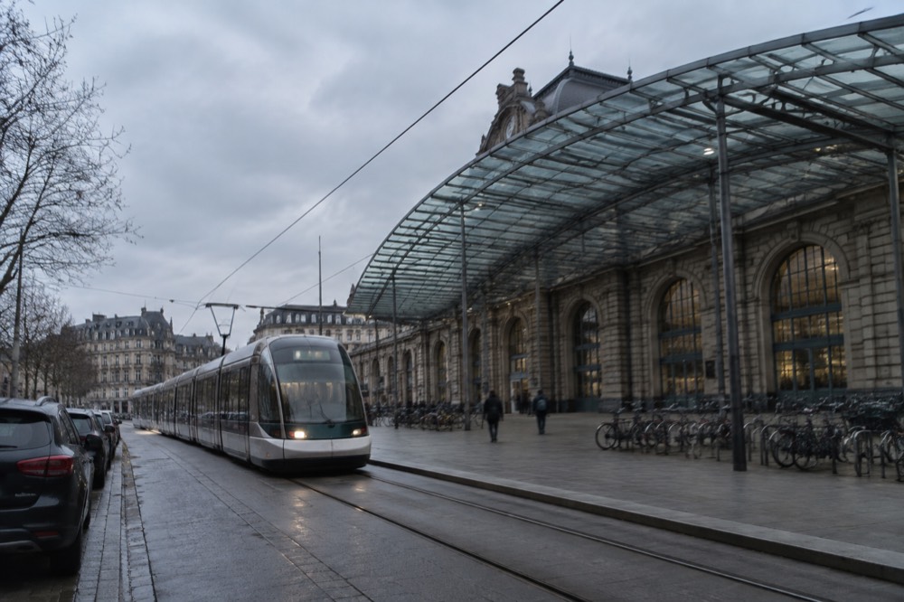 A tram passing a row of parked cars on a wide boulevard in a French city