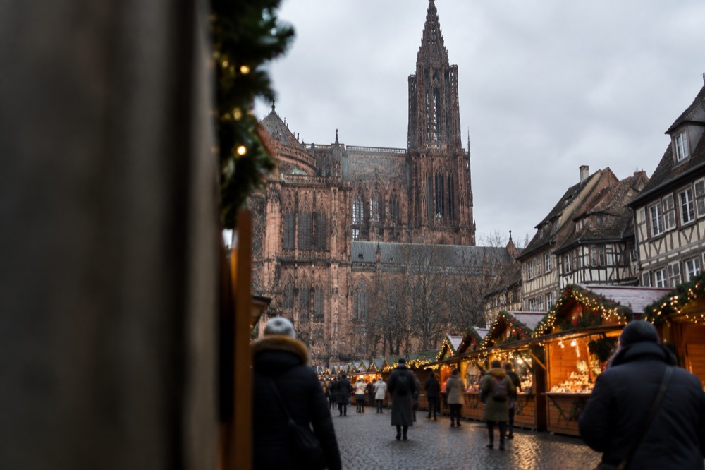 Wooden Christmas chalets with glowing garlands lining a Strasbourg square at dusk