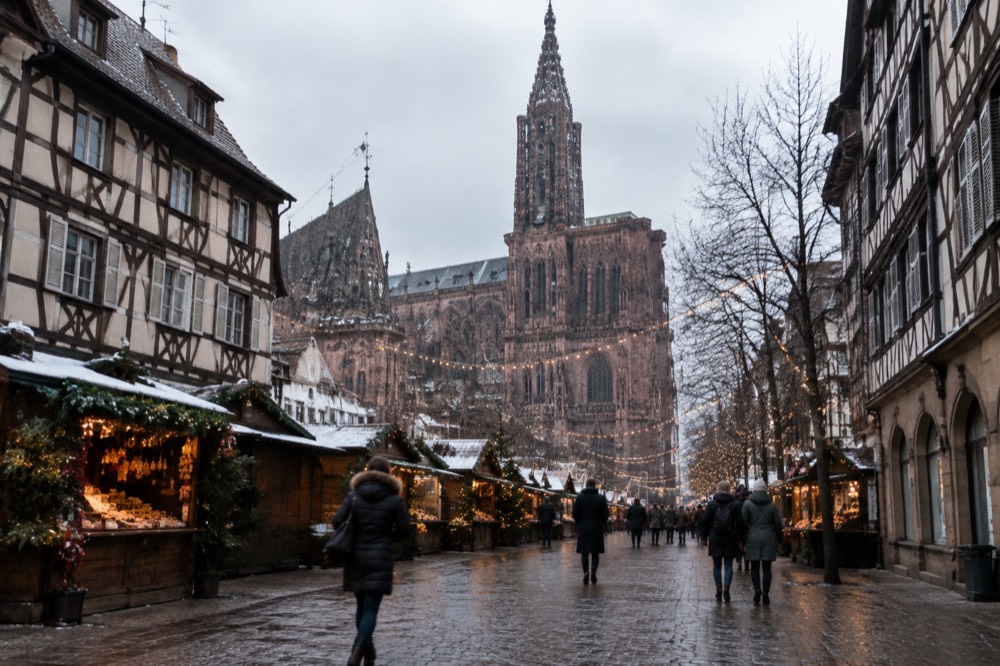 Half-timbered Strasbourg streets decorated with Christmas lights above market stalls