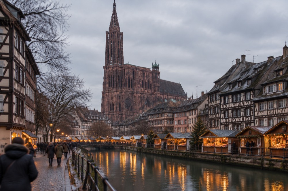Illuminated market chalets reflected in a Strasbourg canal at night