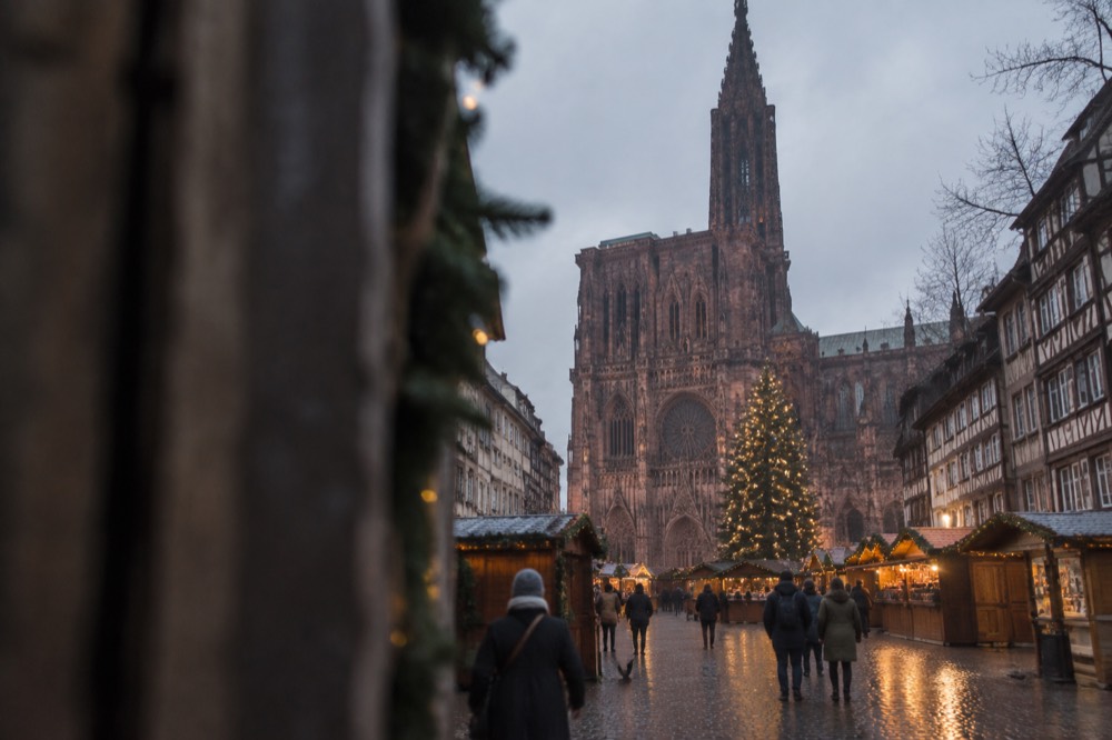 Festive market chalets and a decorated Christmas tree in front of Strasbourg Cathedral at dusk