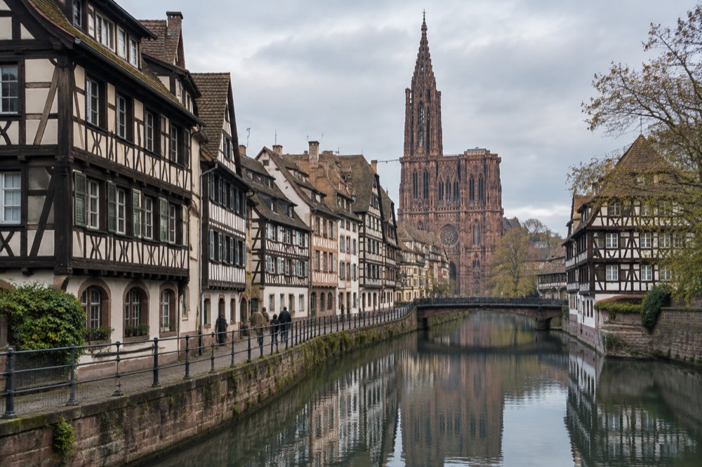 Alsatian half-timbered houses reflected in still canal water