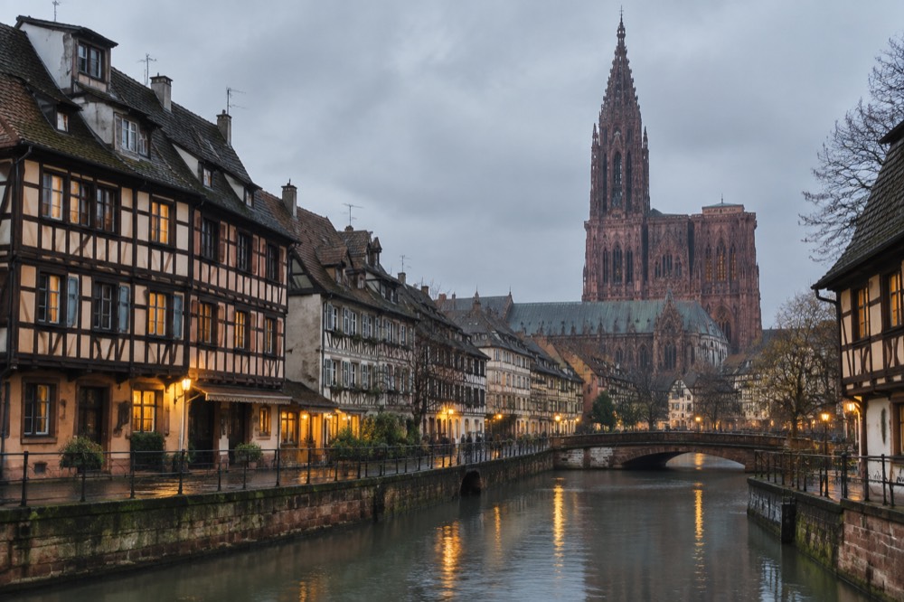 Illuminated half-timbered buildings along a canal in Strasbourg at dusk