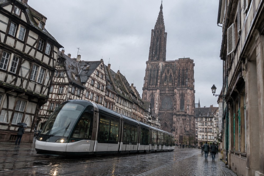 A modern tram passing half-timbered buildings on a street in Strasbourg