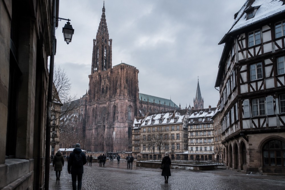 Snow-dusted rooftops and a church spire over Strasbourg rooftops in winter