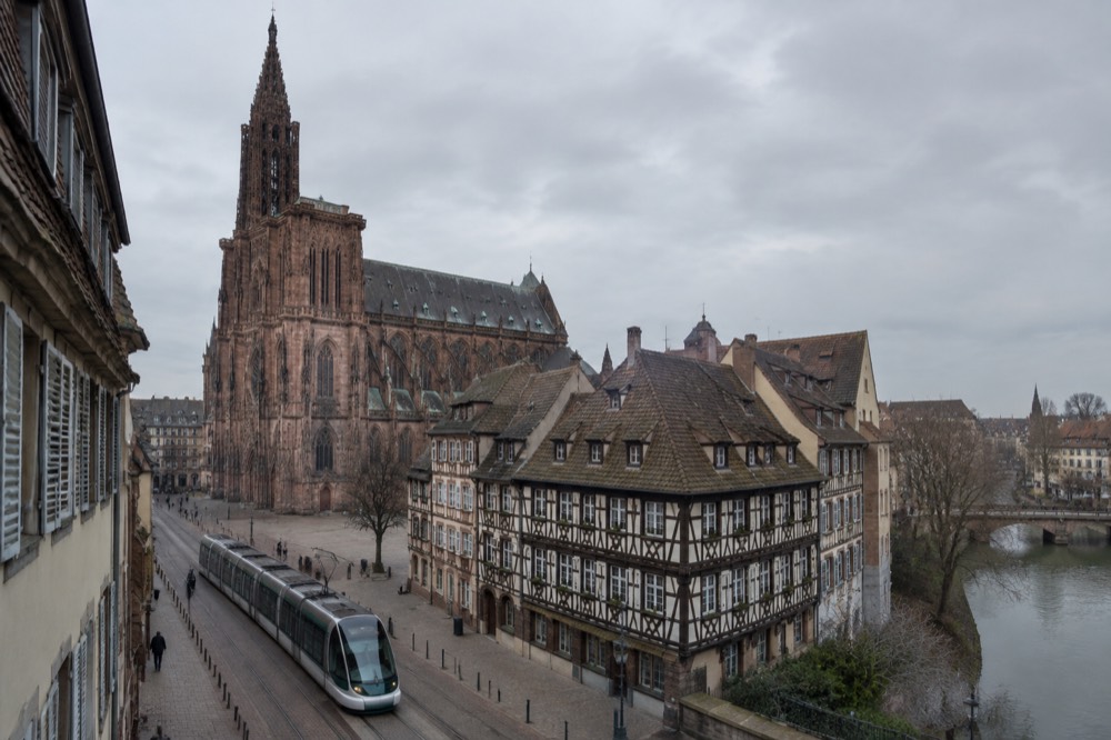 A modern Strasbourg tram passing in front of half-timbered buildings on a city street