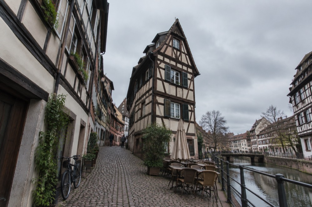 A narrow cobbled lane in the old centre lined with timber-framed buildings and shop signs