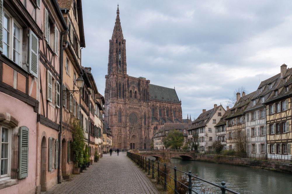 A narrow cobbled lane in old Strasbourg with pastel half-timbered facades and shutters