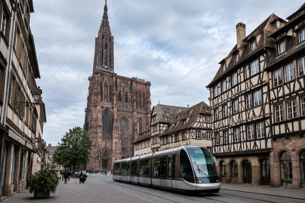 A modern Strasbourg tram passing a half-timbered building on a city street