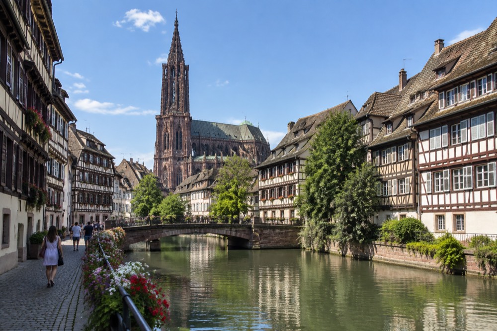 Half-timbered houses along a canal in Strasbourg under a clear blue summer sky